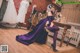 A woman in a purple dress sitting on a wooden floor.