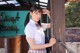 A woman in a school uniform leaning against a wooden door.