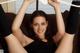 A woman sitting on a couch holding up a pair of white hangers.