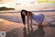 A woman in a blue dress is kneeling in the water.