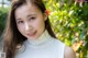 A woman in a white turtle neck top smiles at the camera.