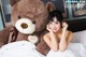 A woman laying in bed next to a large teddy bear.