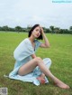 A woman sitting on the grass in a blue dress.