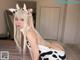 A woman in a cow costume posing on a bed.