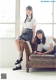 A couple of young women sitting on top of a couch.