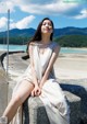 A woman sitting on a concrete wall next to the ocean.