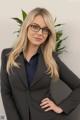 A woman in a business suit and glasses posing for a picture.