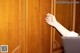 A woman's hand reaching out of a wooden cabinet.