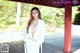 A woman in a white robe standing on a wooden deck.