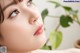 A close up of a woman's face with a plant in the background.