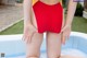 A woman in a red and yellow bathing suit sitting in an inflatable pool.